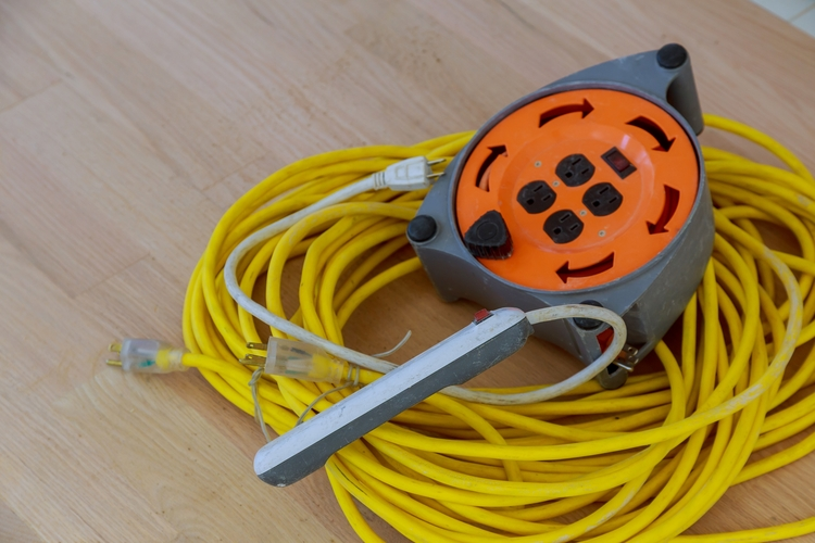 Extensão elétrica enrolada com cabo amarelo e carretel com tomadas múltiplas, ideal para obras, reparos e uso em equipamentos de alta potência.