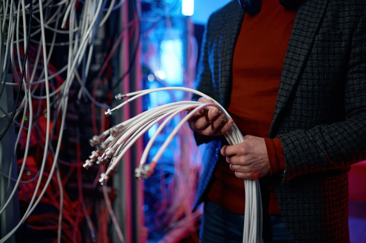 it-man-with-bunch-of-cables-in-hands-in-server-roo-2024-12-04-09-29-50-utc 